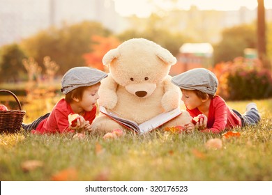 Two adorable little boys with teddy bear friend in the park on sunset, nice back light