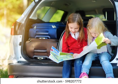 Two Adorable Little Girls Ready To Go On Vacations With Their Parents. Kids Sitting In A Car Examining A Map. Traveling By Car With Kids. 