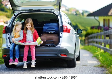 Two Adorable Little Girls Ready To Go On Vacations With Their Parents. Kids Sitting In A Car Examining A Map. Traveling By Car With Kids.