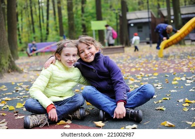 Two adorable school aged tween girls friends having fun in the autumn park, smiling, look into the camera on a beauty autumn day