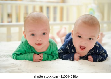 Two adorable twin babies looking into camera and smiling happily. Cute kids during tummy time. Positive lifestyle concept. Happy childhood