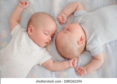 Two Adorable Twin Babies Sleeping In The Same Pose. Top View. Closeup Portrait On Blanket. Safe Sleep Environment For Kids