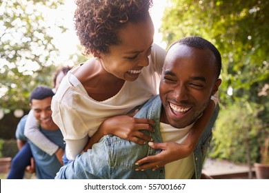 Two adult black couples piggybacking looking at each other - Powered by Shutterstock