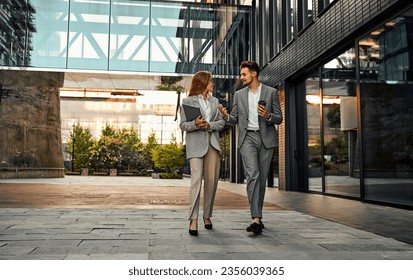 Two adult confident attractive successful stylish handsome business people go to a meeting with partners in business center and discuss project development ideas. Copy space.                       - Powered by Shutterstock