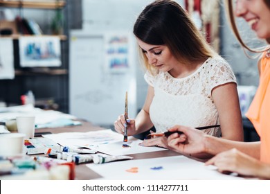 Two Adult Female Students Working On Their Paintings Studying At Art School