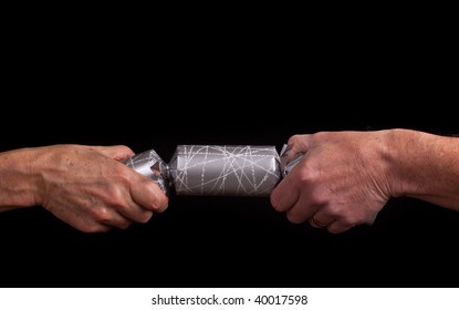 Two Adult Hands Pulling A Christmas Cracker Against A Black Background