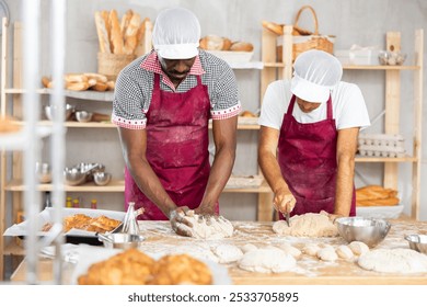 Two adult male bakers kneading dough and cutting dough with scraper - Powered by Shutterstock