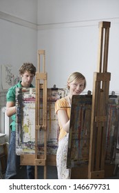 Two Adult Students Painting At Easels In Art Class