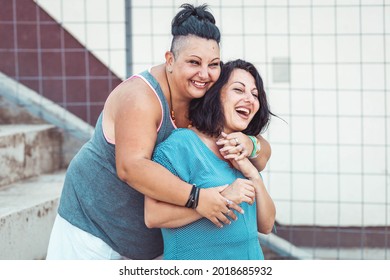 Two Adult Twin Sisters Hugging And Laughing. Different Styles