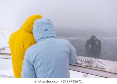 Two adventurers looking at the frozen rock figure of Hvitserkur in Icelandic winter - Powered by Shutterstock