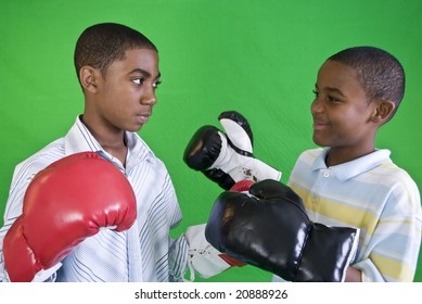 Two African American boys wearing boxing gloves as if ready to spar