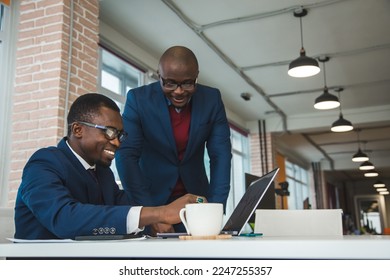 Two African American business partners are working on a laptop together on a joint project. Mutual assistance and establishment of social contacts - Powered by Shutterstock