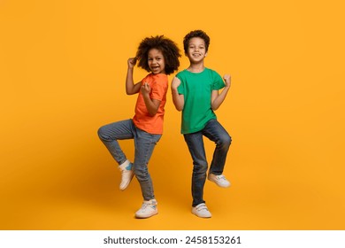 Two African American children, both young and full of energy, are captured mid-air as they jump together. Their bodies are lifted off the ground, displaying pure joy and excitement in their faces. - Powered by Shutterstock