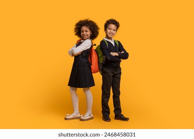 Two African American children dressed in school uniforms are standing on a bright yellow background. They appear to be waiting in line, with their eyes focused ahead - Powered by Shutterstock