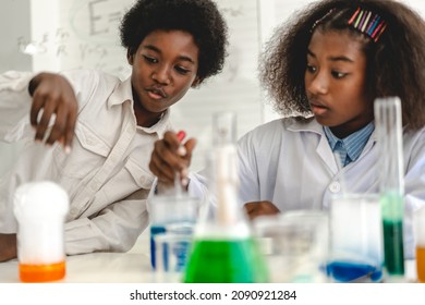 Two african american cute little boy and girl student child learn science research and doing a chemical science experiment making analyzing and mix liquid in test tube on class at school