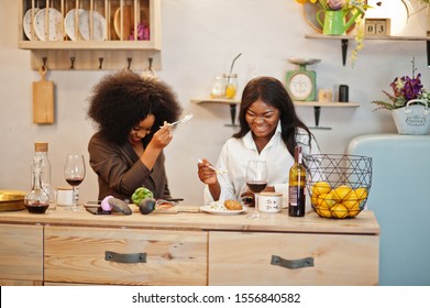 Two African American Female Friends Women Spending Time At Kitchen With Wine. Black Girlfriends  Relaxing At Home And Eat Salad.