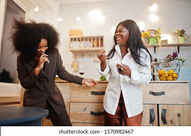 Two African American Female Friends Women Spending Time At Kitchen With Wine. Black Girlfriends  Relaxing At Home And Eat Chocolate.