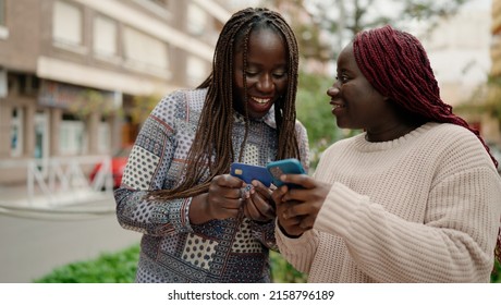 Two african american friends smiling confident using smartphone and credit card at park - Powered by Shutterstock