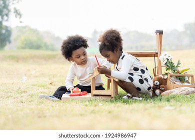 Two African American Little Boy And Girl Playing Toy Together In The Park. Children With Curly Hair Having Fun Together Outdoor. Black Kid People Enjoying Outside