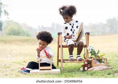 Two African American Little Boy And Girl Playing Toy Together In The Park. Children With Curly Hair Having Fun Together Outdoor. Black Kid People Enjoying Outside