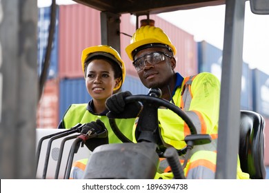 Two African American male and female worker in uniform and helmet driving and operating on diesel container forklift truck at commercial dock site. Multicultural worker - Powered by Shutterstock