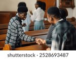 Two african american men happily shake hands at church, showing unity and friendship in a modern sunday service