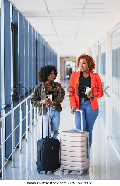 two african american women in airport terminal\
with suitcase