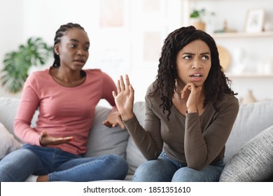 Two African American Women Girlfriends Fighting At Home, Screaming And Gesturing. Black Ladies Sisters Having Quarrel, Annoyed Woman Showing Stop Gesture To Her Screaming Friend