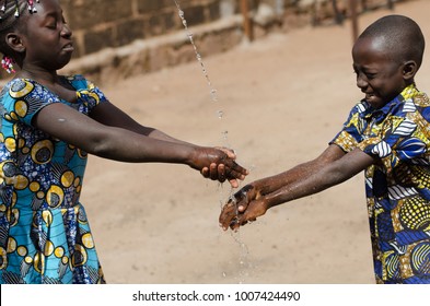 Two African Children Cleaning Hands Outdoors With Fresh Water