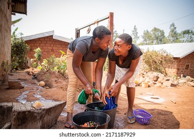 Two African Girls Wash Clothes By Hand Using Soap And A Bucket, Traditional Life In Africa