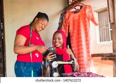 Two African Lady Tailors Viewing Content On A Phone