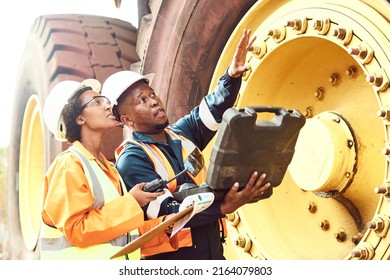 Two African Mine workers are discussing maintenance on a large haul dump truck