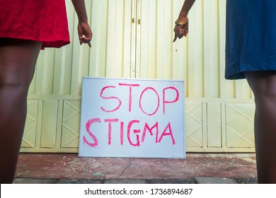 Two African women pointing at a placard creating awareness on stop stigma of people with corona virus infection - concept on black millennials education on avoiding social stigma in covid-19 season