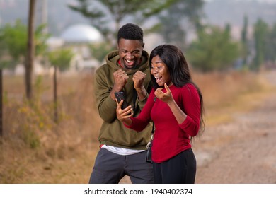 two african youth, guy and lady, viewing content on a phone with excitement