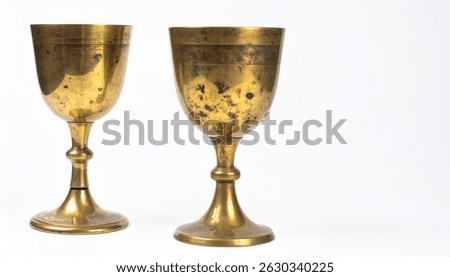 Two aged brass goblets, possibly chalices, display a worn golden patina. They stand on a white background, showcasing their vintage style and ornate design.