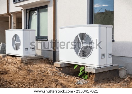Two air source heat pumps installed outside of new and modern city house under construction, green renewable energy concept of heat pump