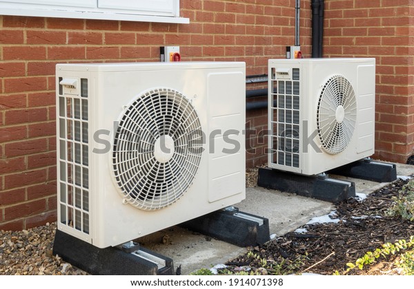 Two air source heat pumps installed on the exterior\
of a modern house