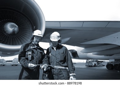 Two Airplane Mechanics With Giant Jet Engine In Background, Blue Toning Idea.