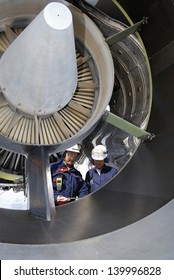 Two Airplane Mechanics Standing Inside Large Jumbo Jet Engine