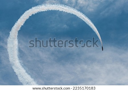 two airplanes fly in parallel describing a white parabolic trajectory over the blue sky. condensation trails. concept synchronization and tuning