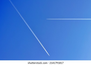 Two Airplanes on the blue sky with long white contrails. 