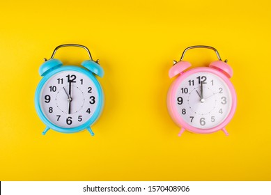 Two Alarm Clocks On A Bright Yellow Background Showing Different Time As The Concept Of A Morning Person And A Night Owl