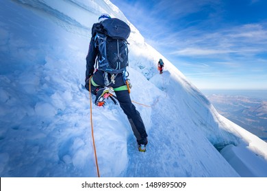 Two alpinists mountaineers climbing ascending over ice snow crevasse crack, extreme sport  mountain climbing. Mont Blanc massif, Europe travel tourism.
