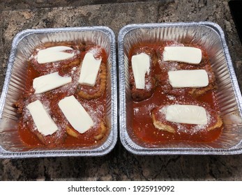 Two Aluminum Trays With Prepared Homemade Chicken Parmesan. The Cutlets Are Fried, The Tomato Sauce Is Cooked, But The Cheese Isn't Melted. This Is An Uncooked Main Course For An Italian Family Meal.