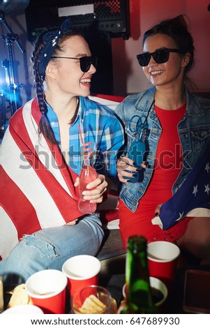 Two American cheering girls with bottles of drinks enjoying party