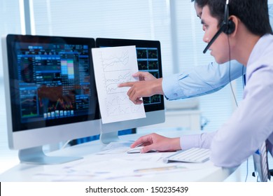 Two analysts discussing financial graphs - Powered by Shutterstock