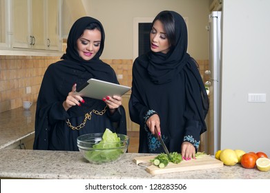 Two Arabian Women Gathering Cooking & Checking Recipe On A Mobile Pad