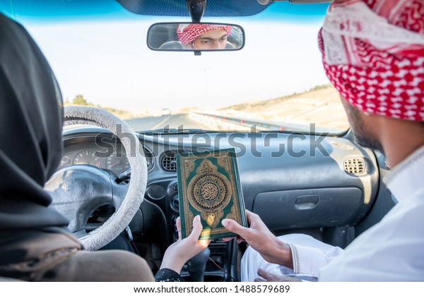 Two arabic\
people holding holy book in their\
hands