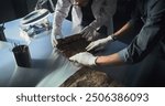 Two archaeologists in gloves carefully roll out ancient Egyptian papyrus on the table in archaeological laboratory. Scientists work with cultural heritage of extinct human civilization. Archaeology.