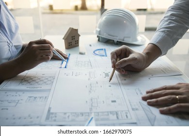 Two architect working at construction site and compass drawing pointing on blueprint with partnership.